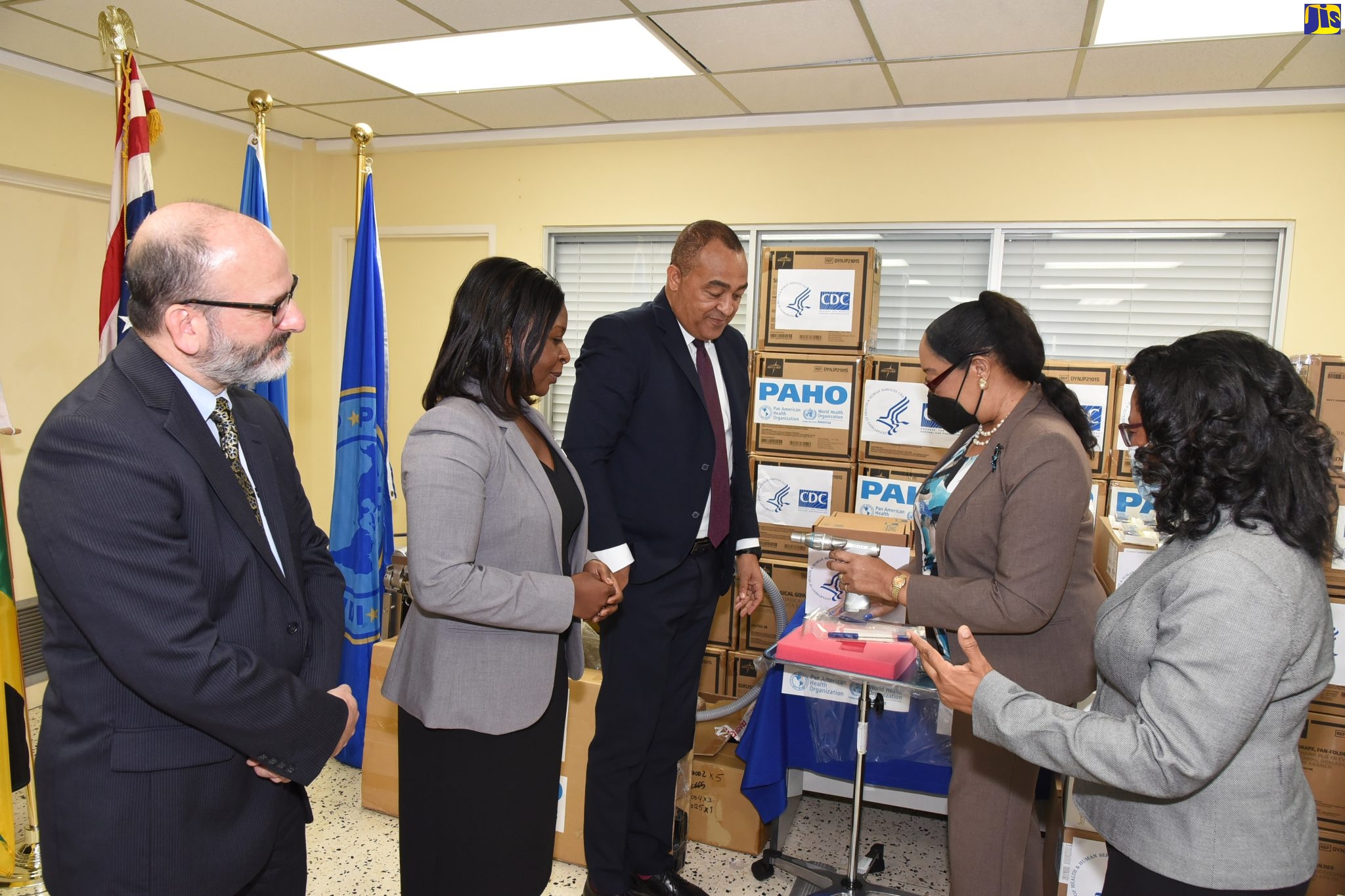 Minister of Health and Wellness, Dr. the Hon. Christopher Tufton (centre), is shown medical equipment and supplies, donated to support the Government for Jamaica’s COVID-19 response, by Pan American Health Organization (PAHO) Advisor, Emergency Preparedness and Response, Dr. Marion Bullock DuCasse. The supplies, valued at approximately $11.94 million (US$78,694.67), were provided by the United States (US) Centers for Disease Control and Prevention (CDC) and the PAHO/World Health Organization (PAHO/WHO). They were formally handed over to Dr. Tufton during a brief presentation ceremony at the PAHO/WHO Country Office, University of the West Indies (UWI) Mona Campus, St. Andrew, on Thursday (October 13). Others (from left) are PAHO/WHO Representative for Jamaica, Bermuda and the Cayman Islands, Ian Stein; US CDC Country Director for Jamaica and the Caribbean Regional Programme, Dr. Emily Kainne Dokubo; and Senior Medical Officer, Bustamante Hospital for Children, Dr. Michelle-Ann Richards-Dawson.