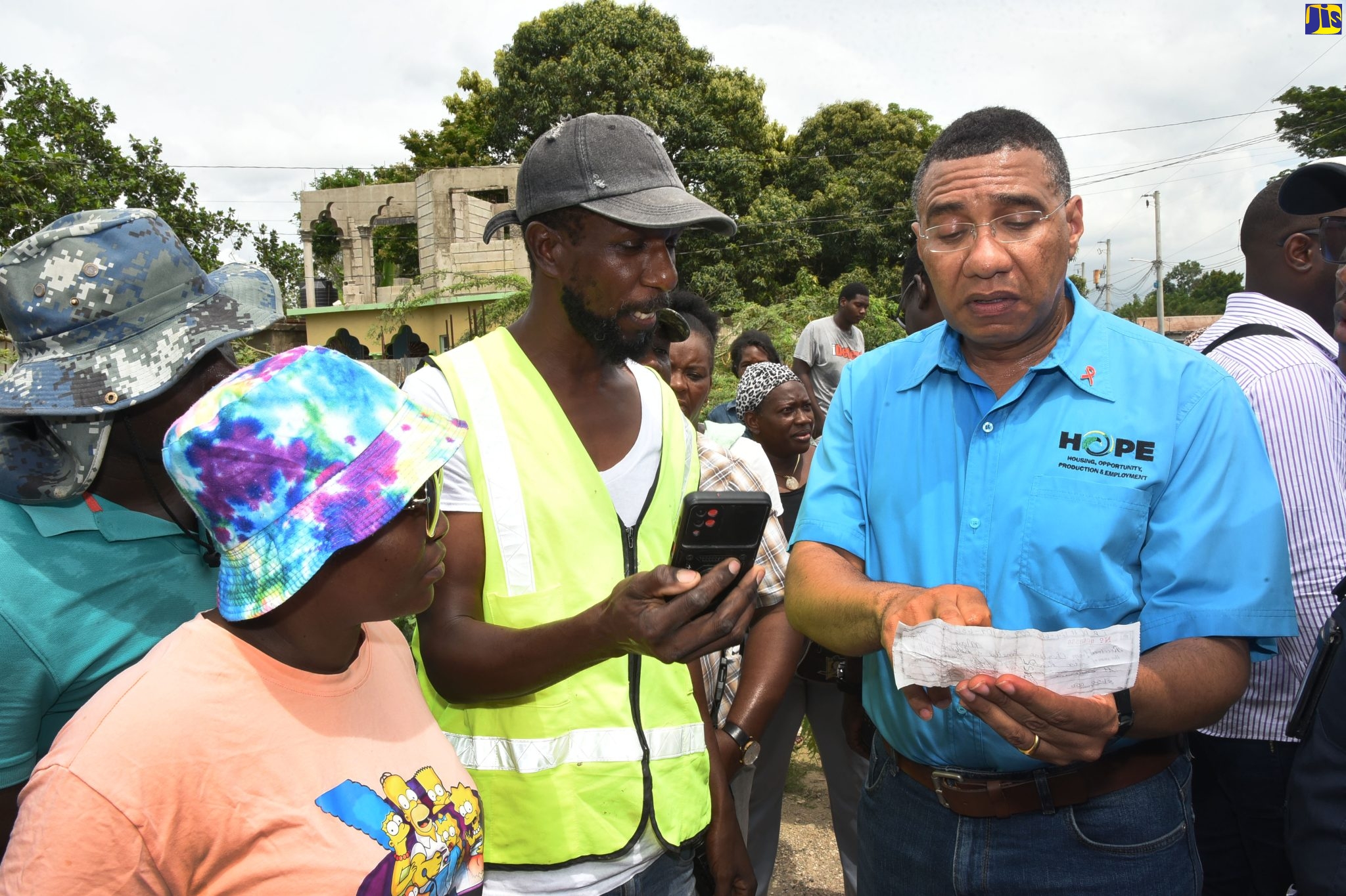 Prime Minister, the Most Hon. Andrew Holness (right), examines a receipt shown to him by Roberto Williams (second right) and Charlene Smellie, as proof of payment for a plot purchased on property adjoining the Clifton community in St. Catherine, to build a house. The Prime Minister visited the area on Friday (October 7) to speak with the residents.