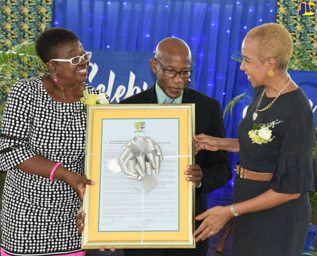 Minister of Education and Youth, Hon. Fayval Williams (right), and Acting Vice Principal, Shortwood Teachers’ College, Dr. Claudette Barrett-March (left), present Dr. Lincoln Phipps with a citation for 27 years of service of the college. Occasion was an appreciation ceremony for outstanding service, held at the institution in Kingston on Wednesday (November 23).