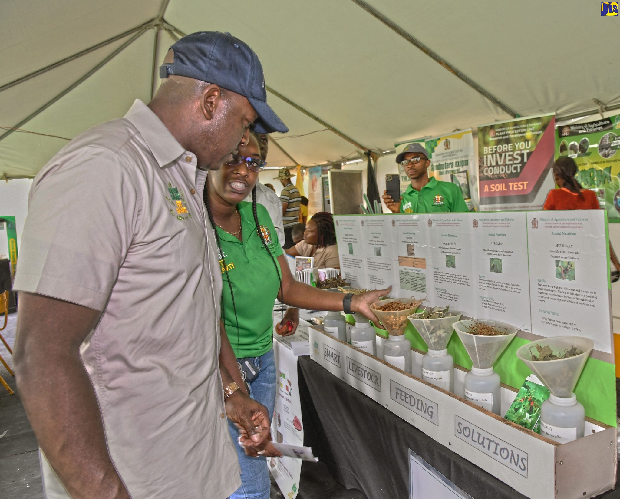 Minister of Agriculture and Fisheries, Hon. Pearnel Charles Jr. (left), is shown a display on smart livestock feeding solutions by Senior Livestock Research Officer, Britally Ricketts, during the Eat Jamaican Day Expo at Devon House in Kingston, on November 25.