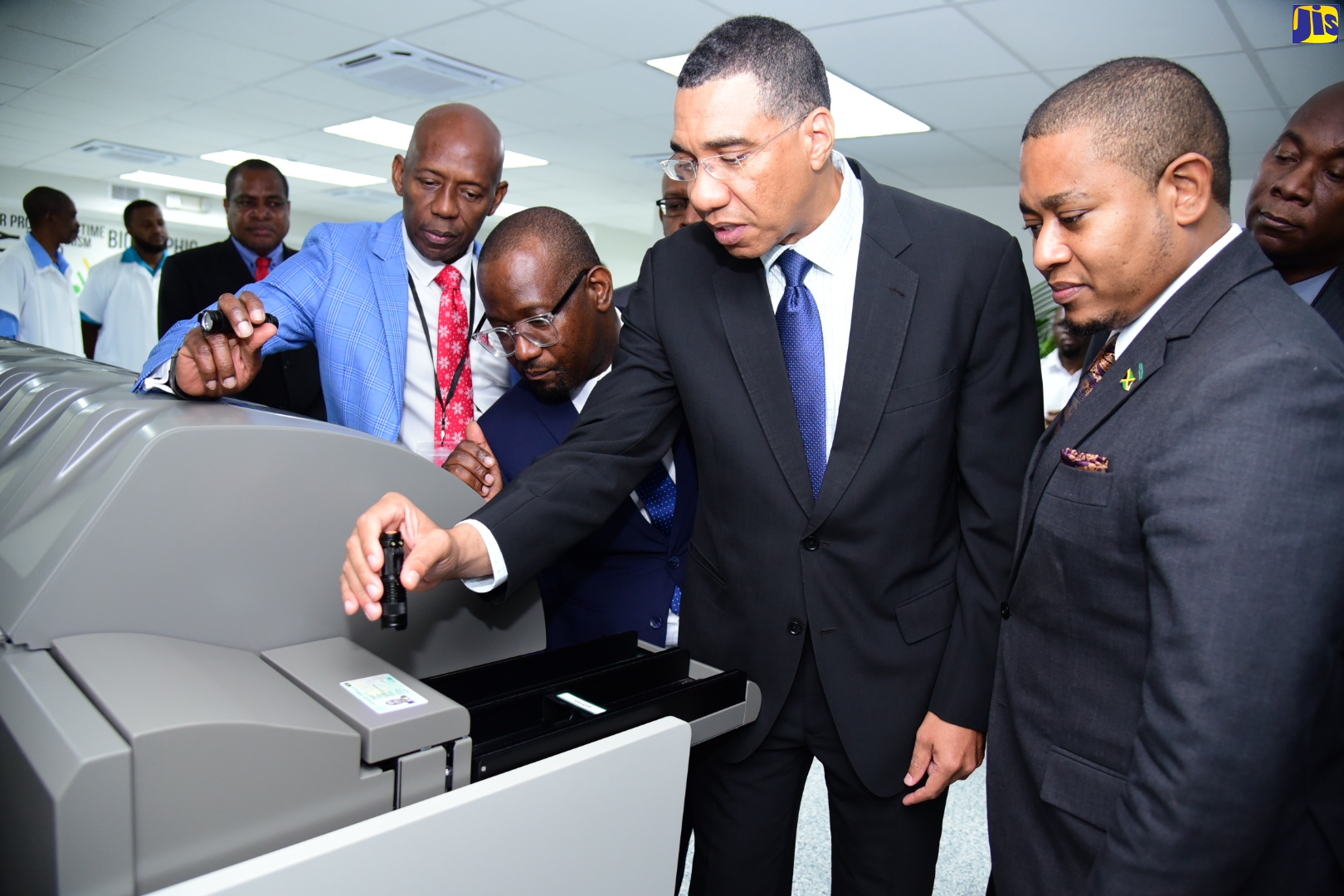 Prime Minister, the Most Hon. Andrew Holness (second right), examines the security features of his newly printed national identification card. Occasion was a tour of the Card Personalisation Centre located at the Jamaica Post Central Sorting Office in Kingston on Tuesday (December 13). Others (from left) are Member of Parliament, St. Catherine North Eastern, Hugh Graham; Programme Director, National Identification System (NIDS), Dr. Warren Vernon; and Minister without Portfolio in the Office of the Prime Minister, Hon. Floyd Green.