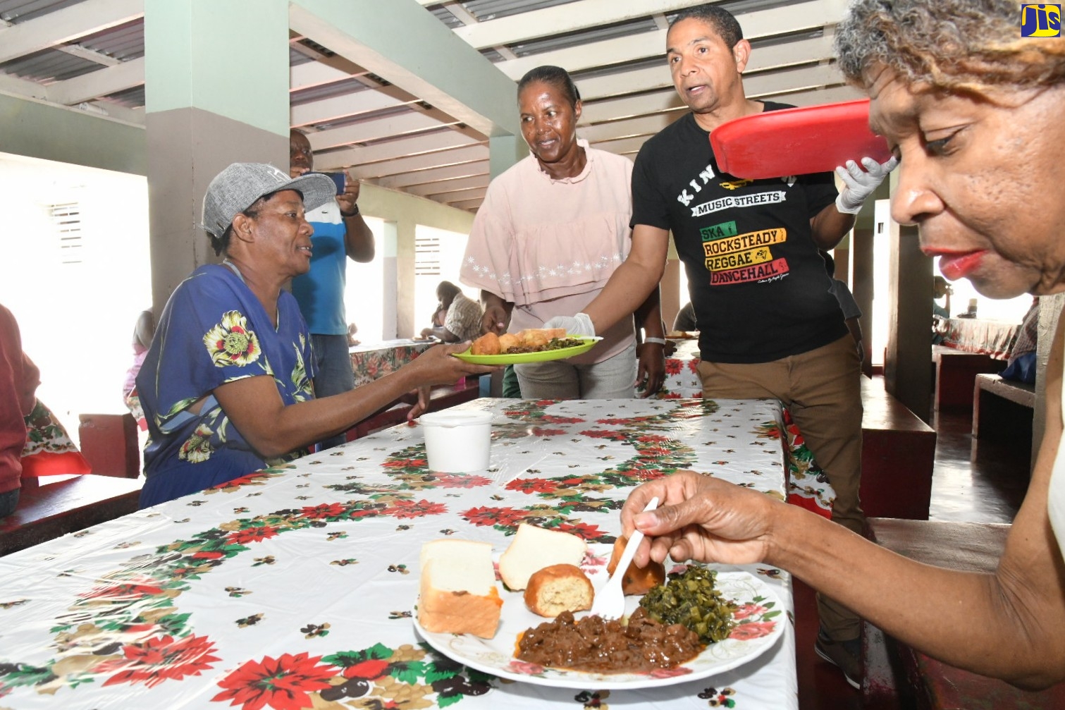 Mayor of Kingston, Senator Councillor Delroy Williams (second right), serves breakfast to several persons living on the streets of the Corporate Area, who were catered to during the Mayor’s Annual Christmas Day Feeding of the Homeless treat at the Marie Atkins Night Shelter on Hanover Street, downtown Kingston, on Sunday (December 25). Assisting Senator Williams is the Kingston and St. Andrew Municipal Corporation’s (KSAMC) Inspector of Poor, Mavis Farquharson (second left). The activity, which is one aspect of the KSAMC’s Homeless Programme, is coordinated by the organisation’s Poor Relief Department.