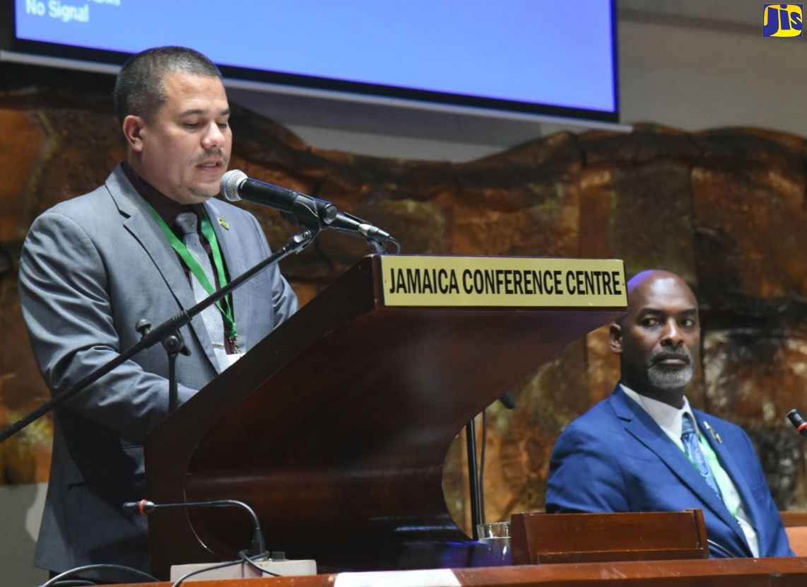 Minister without Portfolio in the Ministry of Economic Growth and Job Creation, Senator the Hon. Matthew Samuda, addresses the inaugural staging of the Forestry Department’s National Forestry Conference held at the Jamaica Conference Centre in downtown Kingston on Wednesday, December 7. Seated at right is Chief Executive Officer of the Forestry Department and Conservator of Forests, Ainsley Henry.
