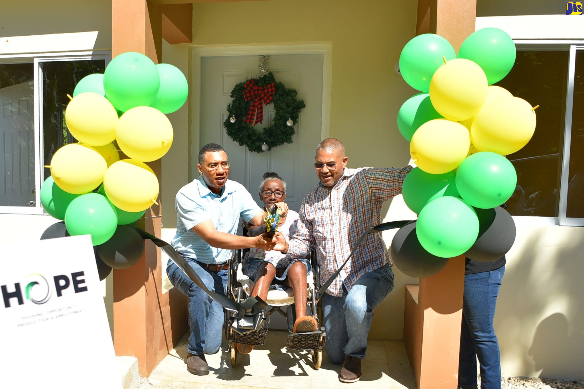 Prime Minister, the Most Hon. Andrew Holness (left) and Member of Parliament, Manchester North Western, Mikael Phillips, assist beneficiary of the Government’s New Social Housing Programme (NSHP), 69-year-old Tesselyn Roach, to cut the ribbon to her new three-bedroom home in Free Town district on Friday (Dec. 16). Ms. Roach lost her house to fire, which also claimed the life of her two-year-old granddaughter, four years ago. She stayed with her cousin, who also lives in the community, prior to receiving her new home. 