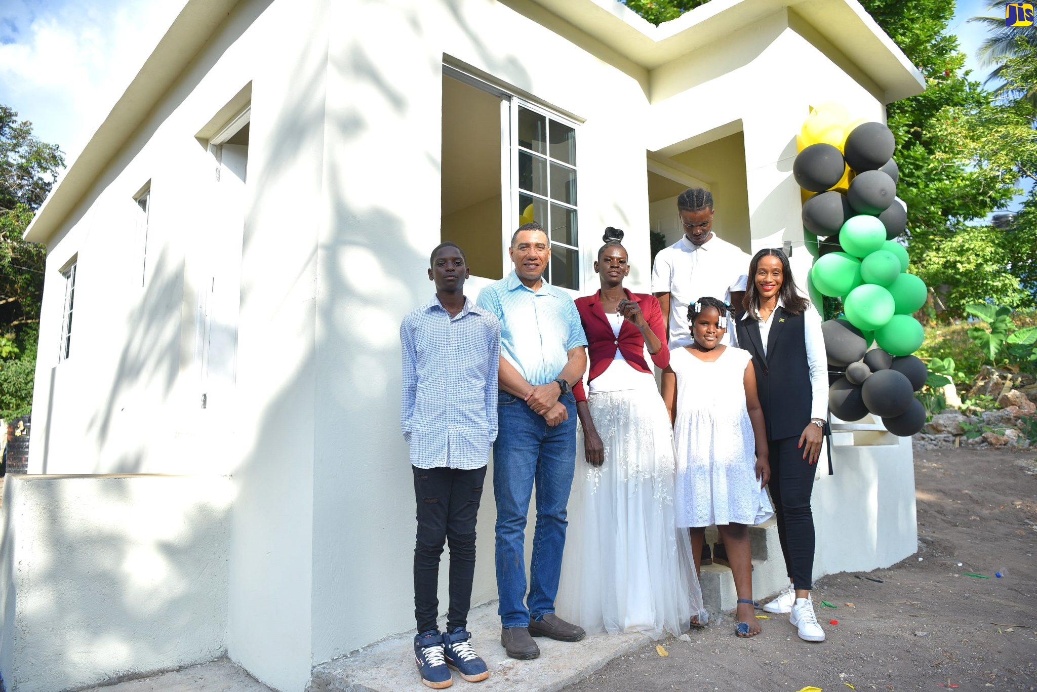Prime Minister, the Most Hon. Andrew Holness (second left) joins  Naderia Wood (third left), and her children (from left), Romeo Smith, Jordan Coley and Shaheim Dunn, in front of their new three-bedroom home in New Hall district in  Manchester Central on Friday (Dec.16). Occasion was the official hand over of the unit provided under the New Social Housing Programme (NSHP).  Sharing the moment is Member of Parliament for the area, Rhoda-Moy Crawford.