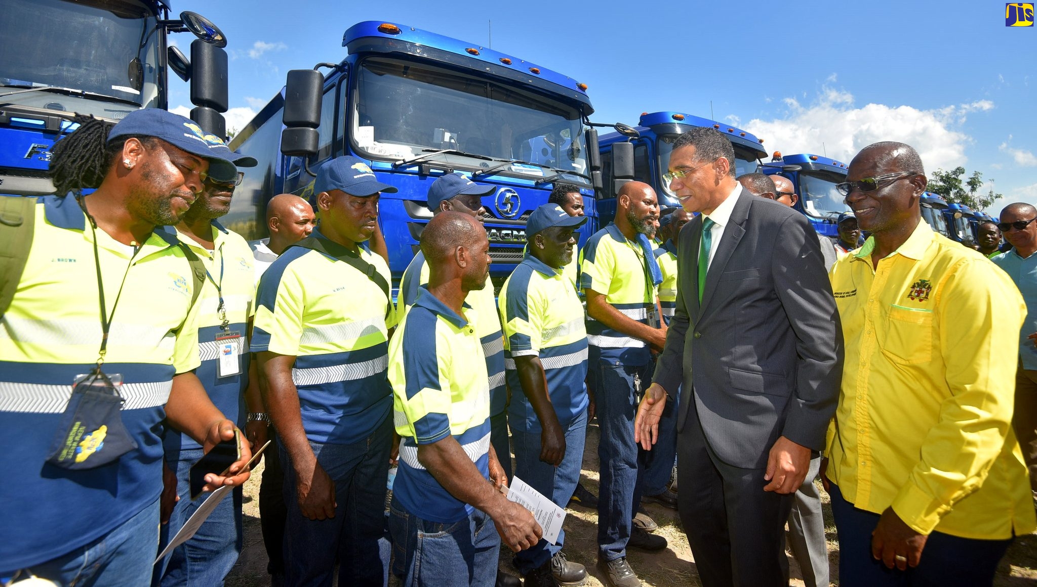 Prime Minister, the Most Hon. Andrew Holness (second right), and Minister of Local Government and Rural Development, Hon. Desmond McKenzie (right), interact with National Solid Waste Management Authority (NSWMA) employees, during the official handover ceremony for 50 new trucks and 10 motorcycles acquired for the agency. The ceremony was held at National Heroes Park in Kingston recently