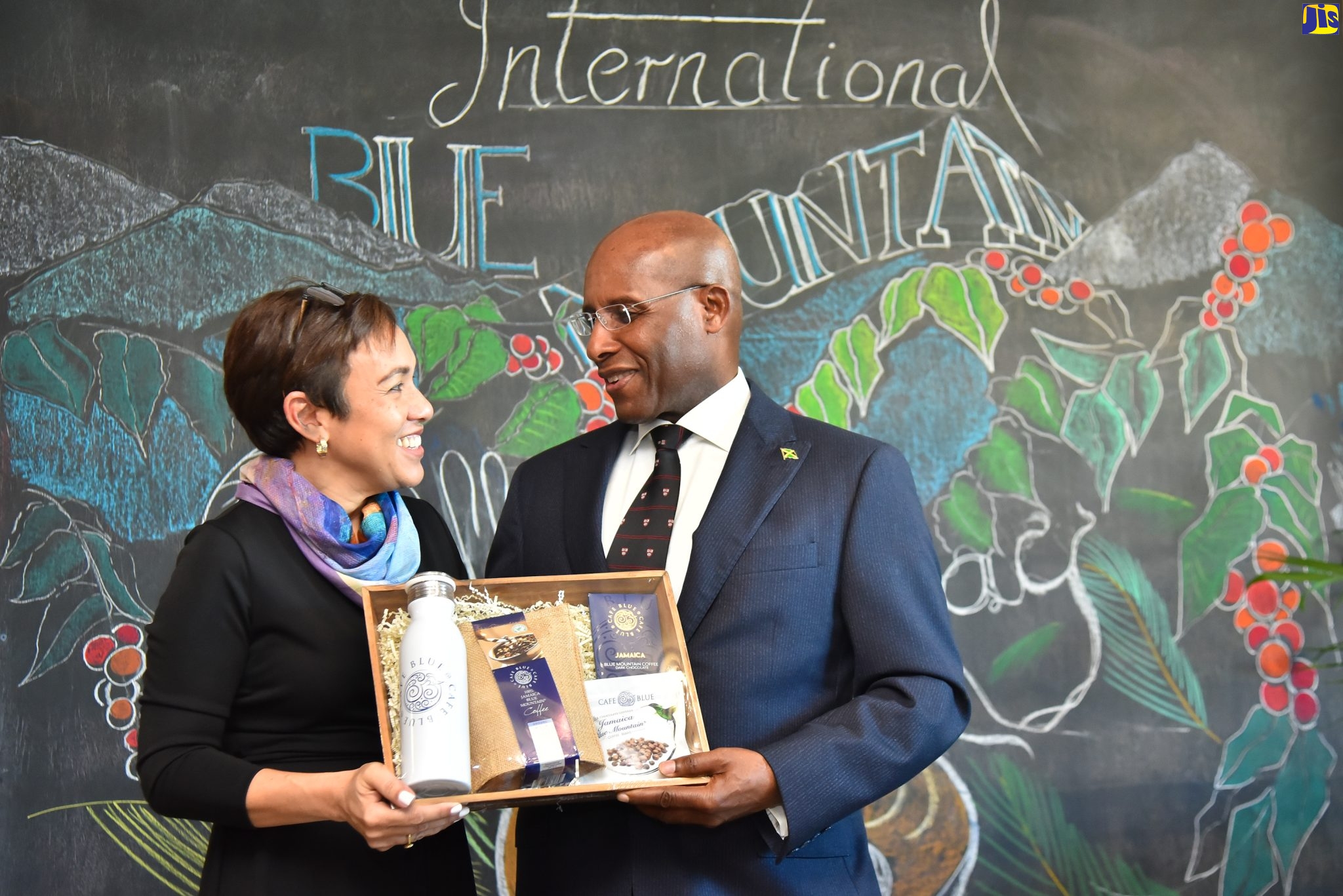 Minister of Industry, Investment and Commerce, Senator the Hon. Aubyn Hill (right), receives a package from the Director, Coffee Traders Limited, Jacqueline Sharp, during the 2023 staging of Jamaica Blue Mountain Coffee Day at Café Blue in St. Andrew, on Monday (January 9).