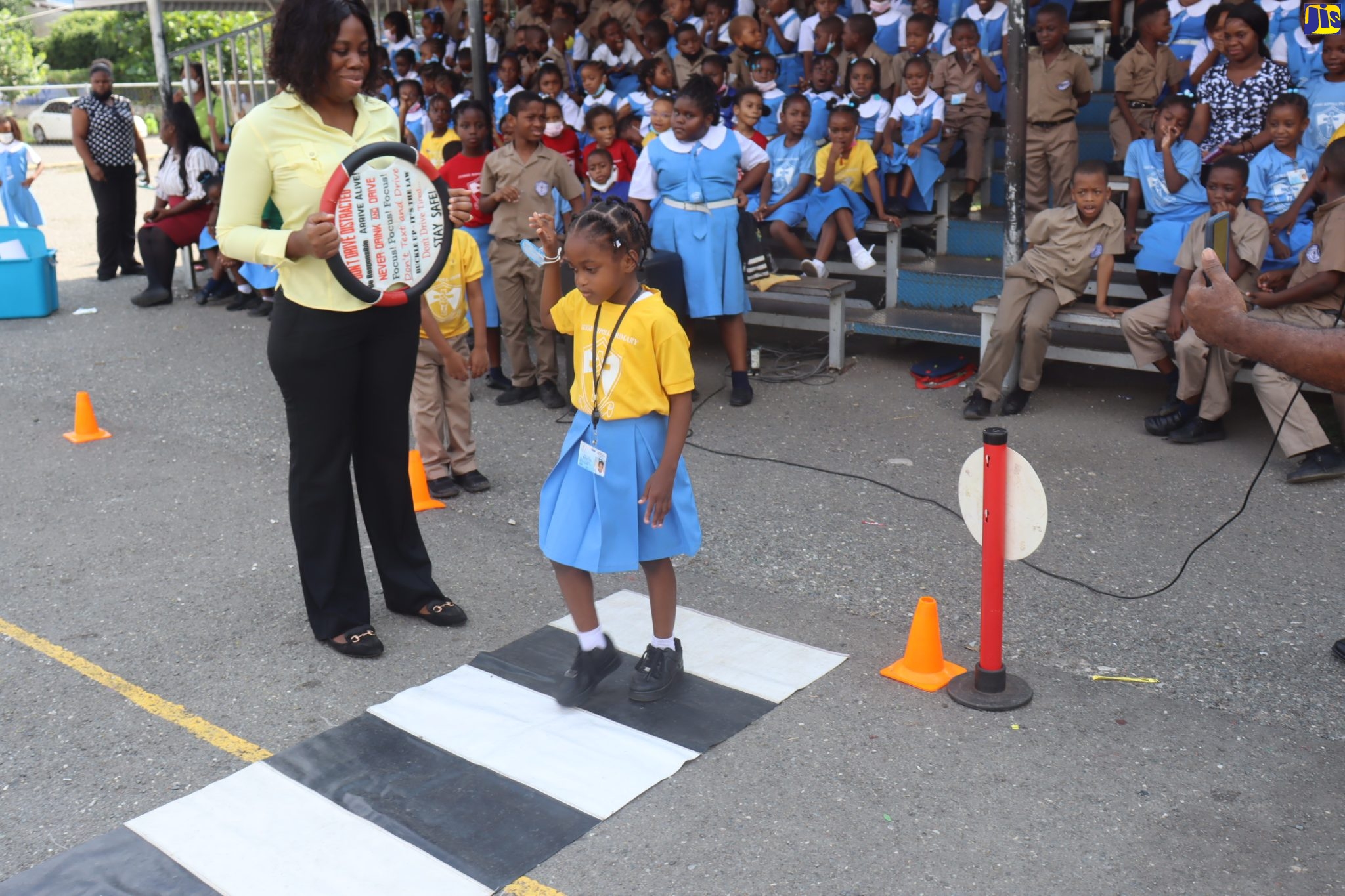 A student of Jessie Ripoll Primary School in Kingston practises the ‘Kerb Drill’, which teaches children to raise their hand while crossing the road and observing their surroundings to ensure it is safe to do so.  