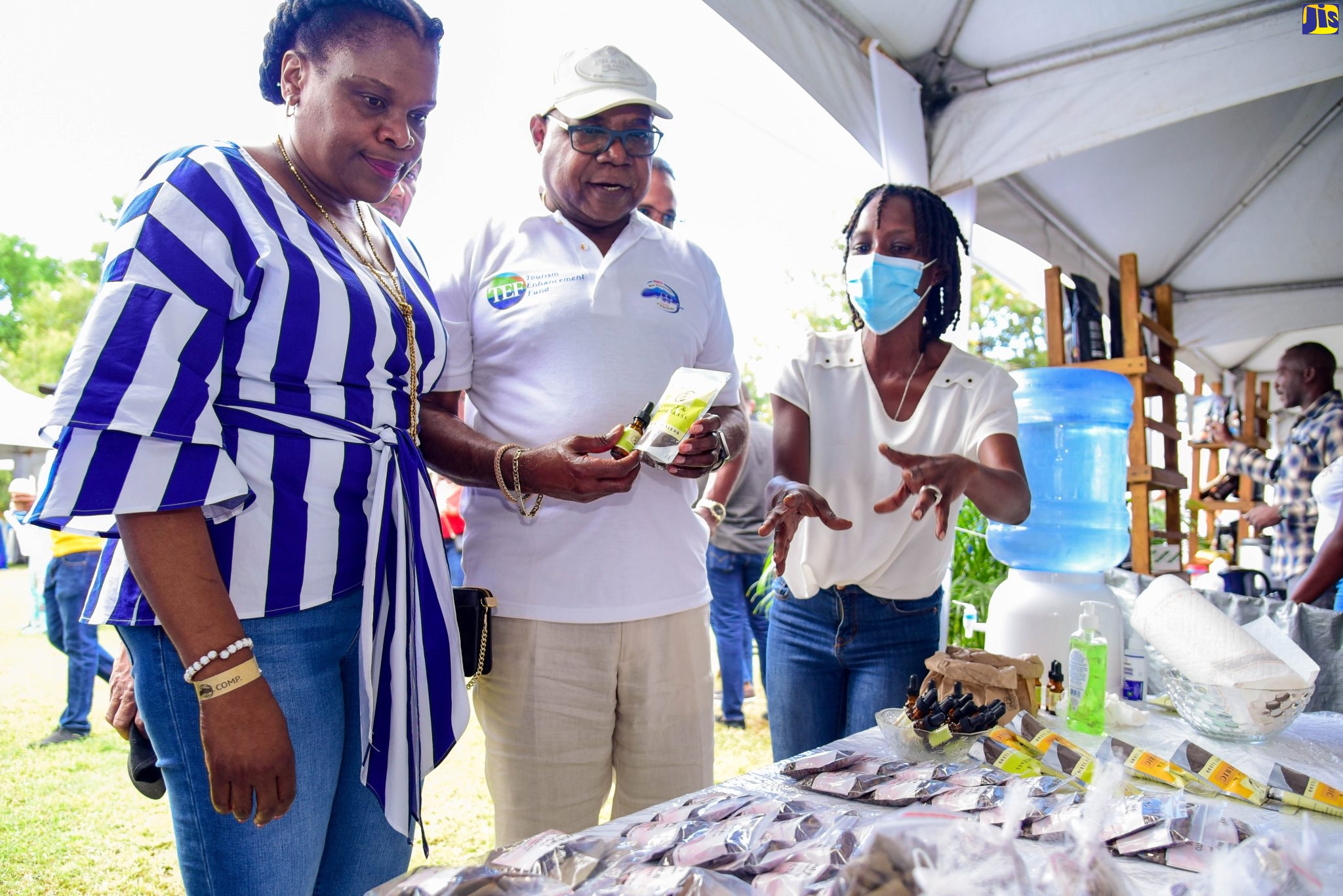 Tourism Minister, Hon. Edmund Bartlett (centre) and Permanent Secretary in the Tourism Ministry, Jennifer Griffith (left), are shown displays manufactured by Glo Coffee Products by company owner Ano Sewell, during last year’s staging of the Jamaica Blue Mountain Coffee Festival Marketplace at Devon House in Kingston.