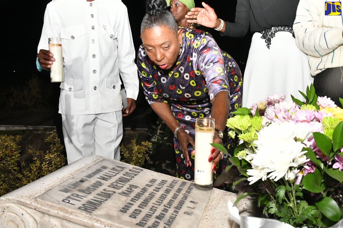 Minister of Culture, Gender, Entertainment and Sport, Hon. Olivia Grange places a candle on the grave of former Jamaican religious revivalist, painter, and sculptor, Mallica “Kapo” Reynolds. This was done in commemoration of the 112th anniversary of his birth, on Friday (February 10) at the National Heroes Park in Kingston.