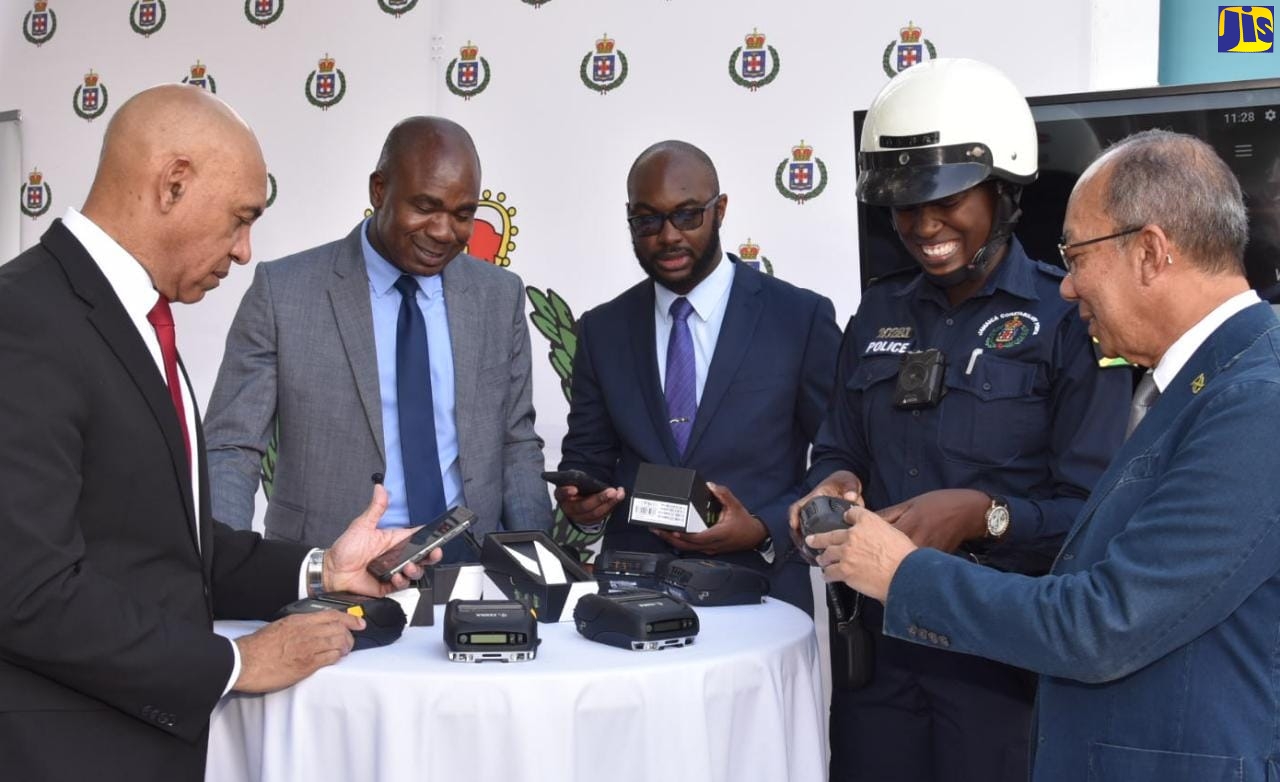 Minister of National Security,  Hon. Dr. Horace Chang (right), inspects a Traffic Ticket Management System (TTMS) handset, at a handover ceremony for 750 mobile handheld printers to the Jamaica Constabulary Force (JCF), at the Office of the Commissioner of Police, St. Andrew, recently.  Others examining the devices (from left) are Commissioner of Police, Major General Antony Anderson; Minister of State in the Ministry, Hon. Zavia Mayne; Senior Director, Major Technology Transformation Branch in the Ministry, Emil Holgate and Woman Constable, Morata Murdoch. 