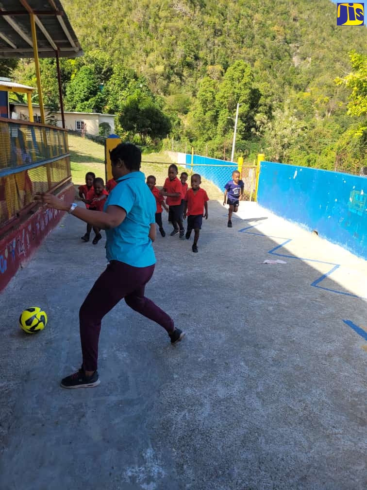 Director of Procurement at the Early Childhood Commission, Joleesa Courts, participates in a football game with boys at the Minna Carr Basic School in Bull Bay, St. Andrew, during Play Day activities on February 1.