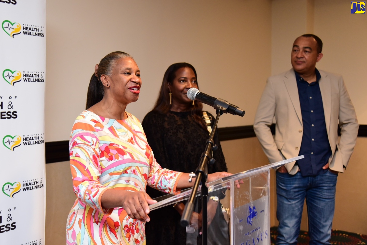 Minister of Health, Dr. the Hon. Christopher Tufton (right), looks on while Head of a gynaecological team on a medical mission that came to the island, Dr. Monique Jones (left), speaks at a reception for the group, held at The Jamaica Pegasus hotel in New Kingston, recently. Also pictured is Jamaican-born United States (US) based critical care nurse, Dr. Sandra Lindsay.
