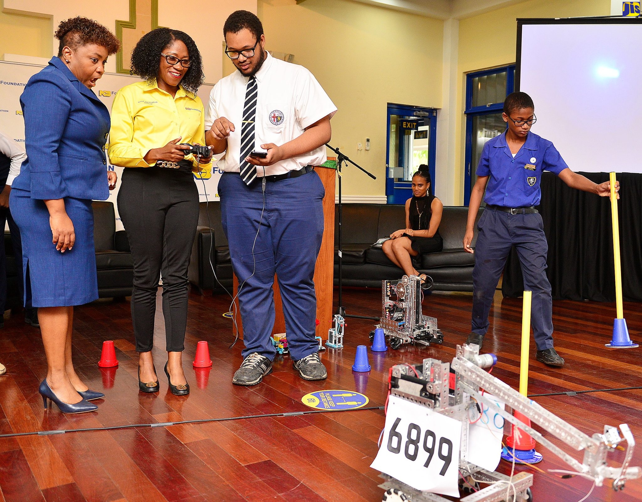 Acting Assistant Chief Education Officer in the Ministry of Education and Youth, Sophia Forbes Hall (left), looks on in amazement as Chief Executive Officer of the NCB Foundation, Nadeen Matthews Blair (centre), operates a robot built by the Jamaica College (JC) robotics team. Member of the  JC team, Michael Woods, provides instructions on how to operate the robot.  Occasion was Wednesday’s (February 15) launch of the NCB Foundation’s National Robotics Championship at the NCB Wellness and Recreation Centre in St. Andrew.  The competition will be held at the JC Auditorium from February 24 to 25.
