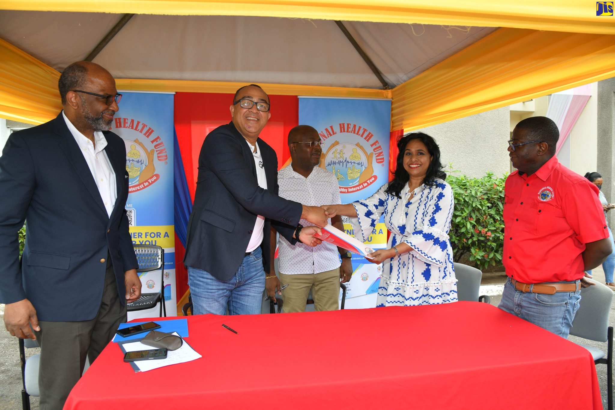 Minister of Health and Wellness, Dr. the Hon. Christopher Tufton (second left), presents a signed contract to Assistant Manager at Fleet Diagnostic Laboratory, Neesha Graham (second right), during the launch of the National Health Fund (NHF) Prostate Specific Antigen (PSA) Test facility on February 4, at the Jamaica Cancer Society (JCS), on Lady Musgrave Road in St. Andrew. Looking on are (from left) Chairman of the JCS, Earl Jarrett; Acting Chairman of the NHF, Shane Dalling and Chief Executive Officer of the agency, Everton Anderson.