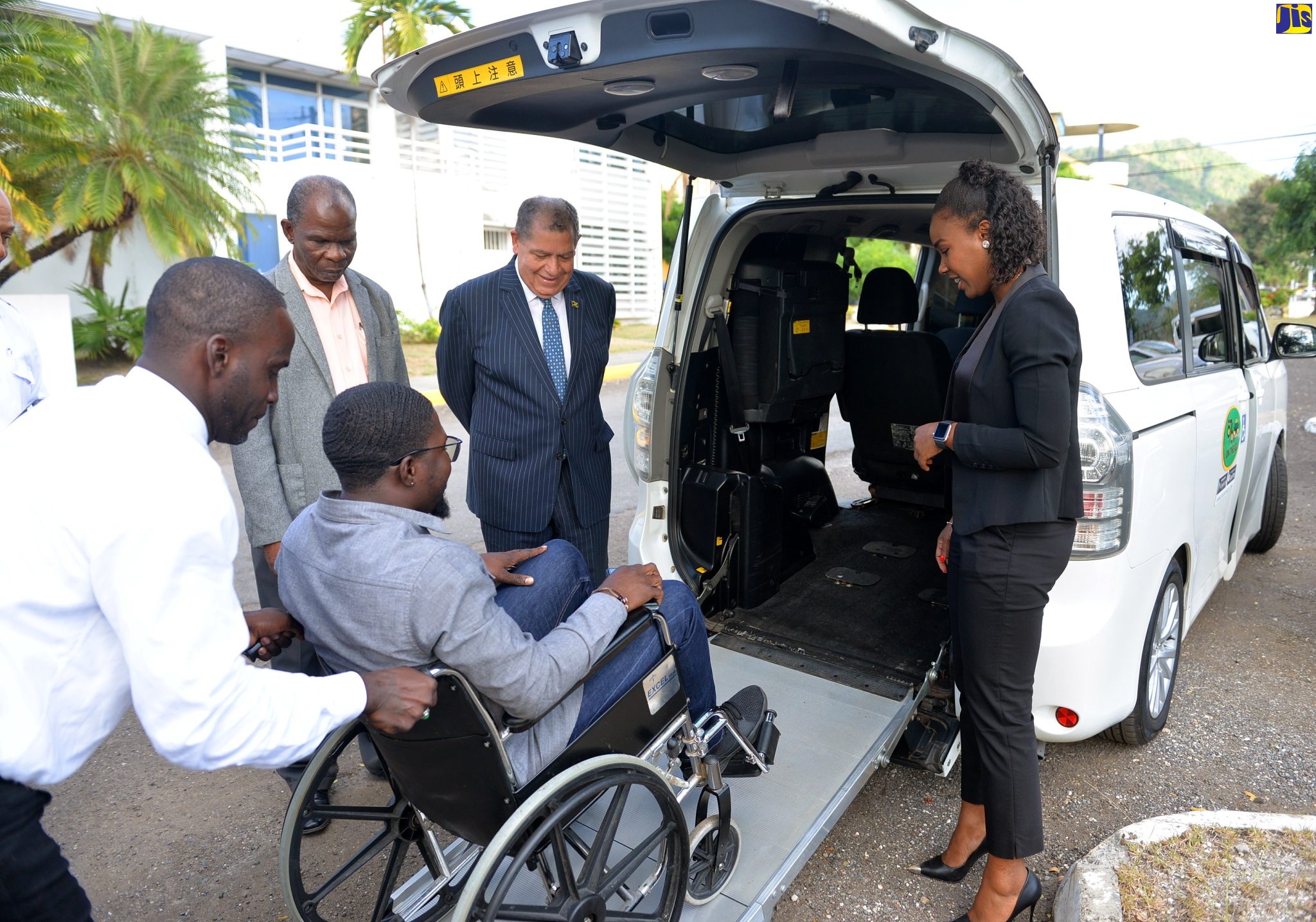 Minister of Transport and Mining, Hon. Audley Shaw (second right), looks on while Executive Driver for 876 On The Go Taxi Service, Dudley Carter (left), assists a wheelchair-bound passenger to enter a vehicle. Occasion was the launch of the taxi service’s facility for disabled persons at the University of Technology (UTech) in St. Andrew recently. Also observing (from second left) are President of the Transport Operators Development Sustainable Services (TODSS), Egeton Newman and Chief Executive Officer and Founder of 876 On The Go Taxi Service, Olivia Lindsay.