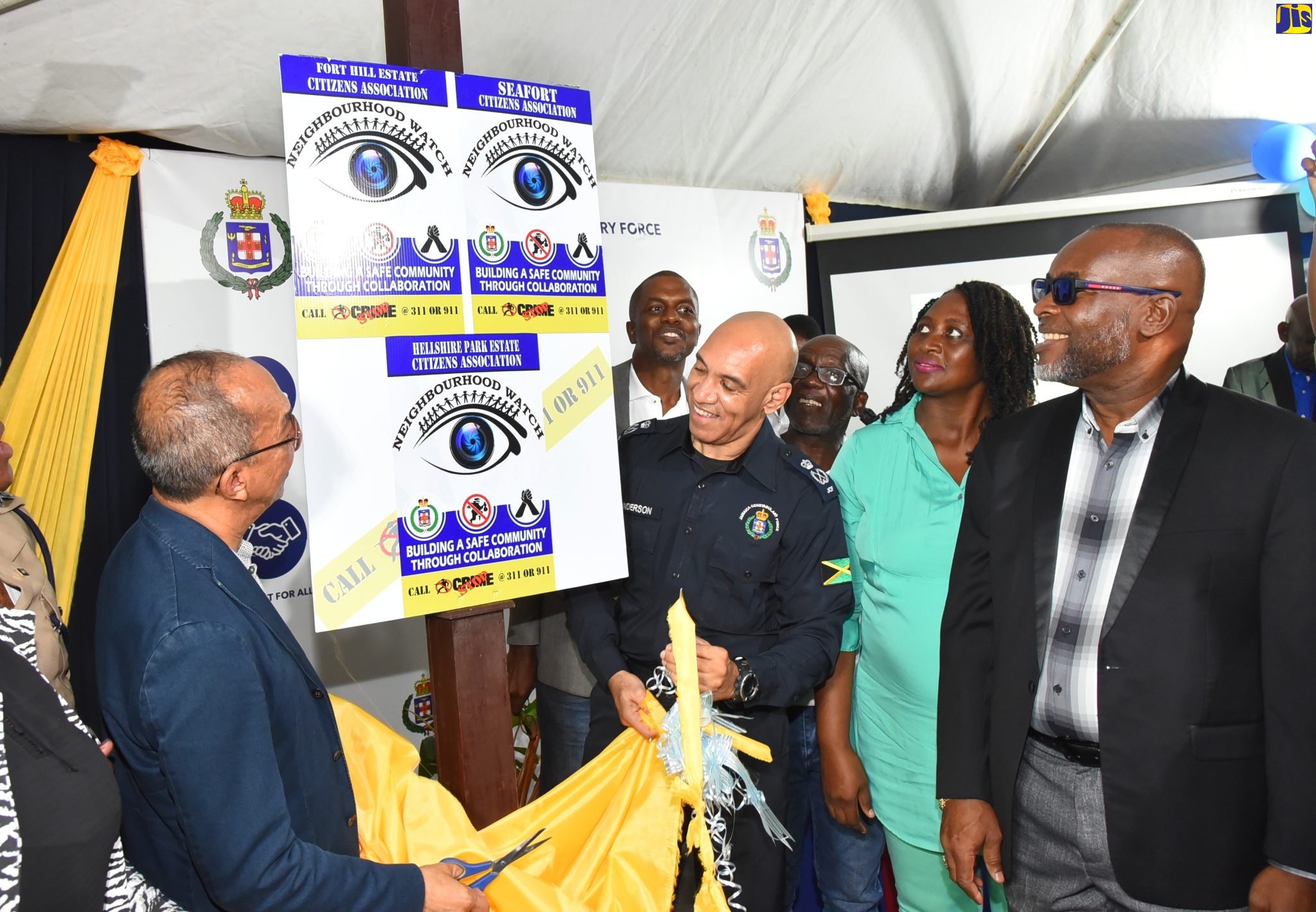 Minister of National Security, Hon. Dr. Horace Chang (left) and Commissioner of Police, Major General Antony Anderson (third right), lead the unveiling of a sign during the official launch of a neighbourhood watch programme for communities in Hellshire, Portmore, St. Catherine. The event took place at the Hellshire Park Shopping Centre on March 25. Sharing the moment (at right) is Mayor of Portmore, Councillor Leon Thomas.