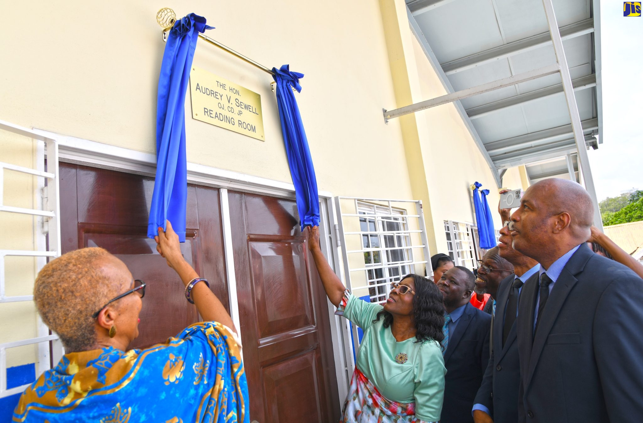 Minister of Education and Youth, Hon. Fayval Williams (left) and Permanent Secretary in the Office of the Prime Minister Audrey Sewell, unveil the Audrey V. Sewell Library and Reading Room, located at the New Hope Preparatory School in Central Kingston, recently. Among those looking on is Chairman of the school, Duane Muirhead (right)