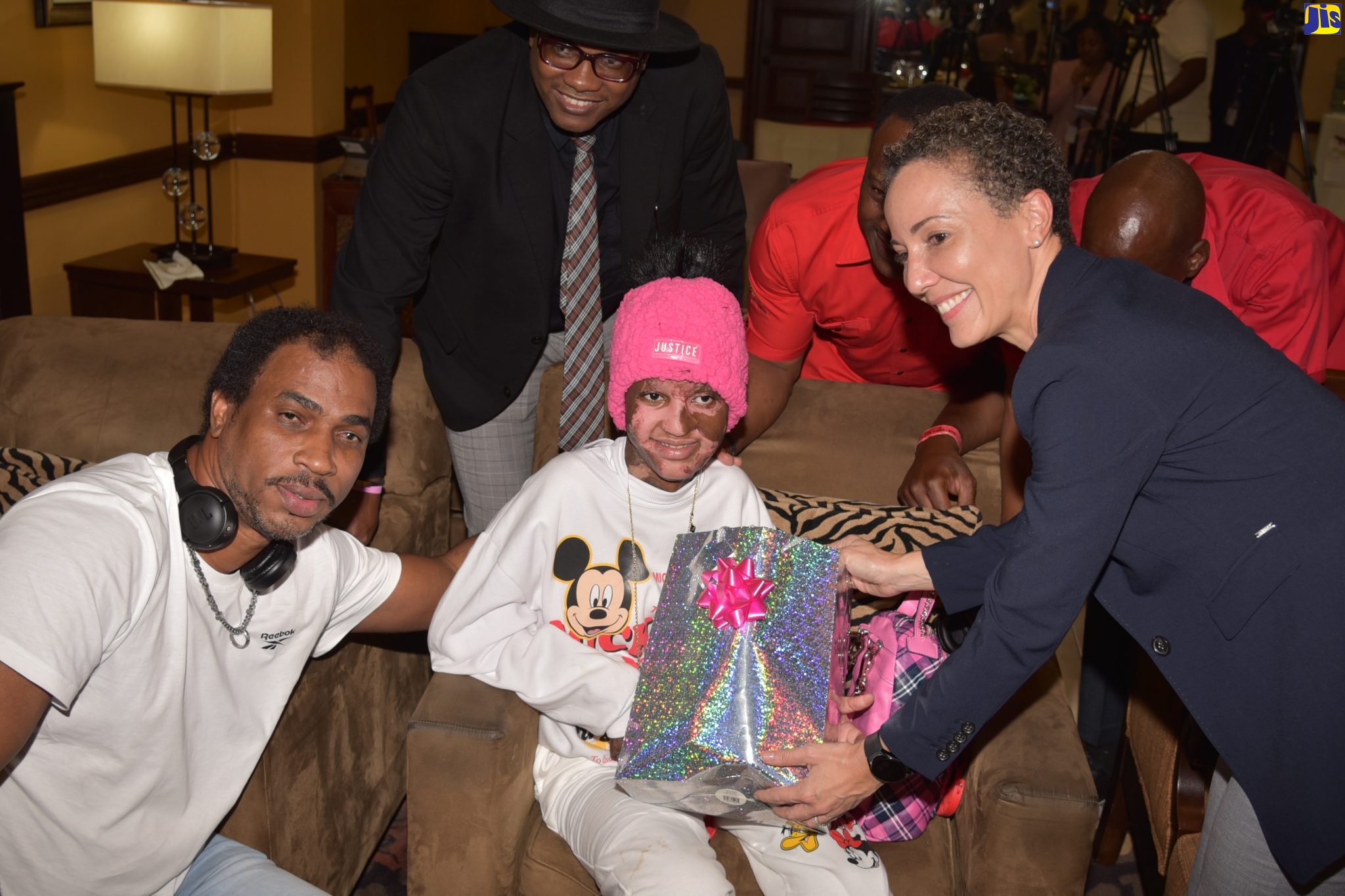 Minister of Foreign Affairs and Foreign Trade, Senator the Hon. Kamina Johnson Smith (right), presents a welcome home gift to 13-year-old burn victim, Adrianna Laing (seated) who returned to island on Thursday (March 30) after successful treatment overseas. Sharing the moment (from left) are her father, Adrian Laing; and members of the Sanmerna Foundation – Project Manager, Stephen Joseph; Managing Director, Robert White; and Board Director, Mark White. A homecoming ceremony was hosted by the Ministry at the Norman Manley International Airport in Kingston.