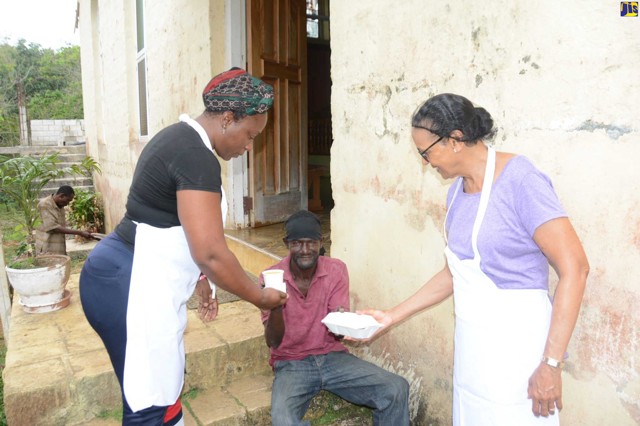 Members of the Balaclava Senior Citizens’ Club in St. Elizabeth, Keesha Stampp-Gardner (left) and Cherry Johnson (right), hand over a cooked meal to an indigent known only as “Gary” in the community as part of the club’s outreach initiative to cook and prepare meals for the elderly, shut-ins and the indigent.

