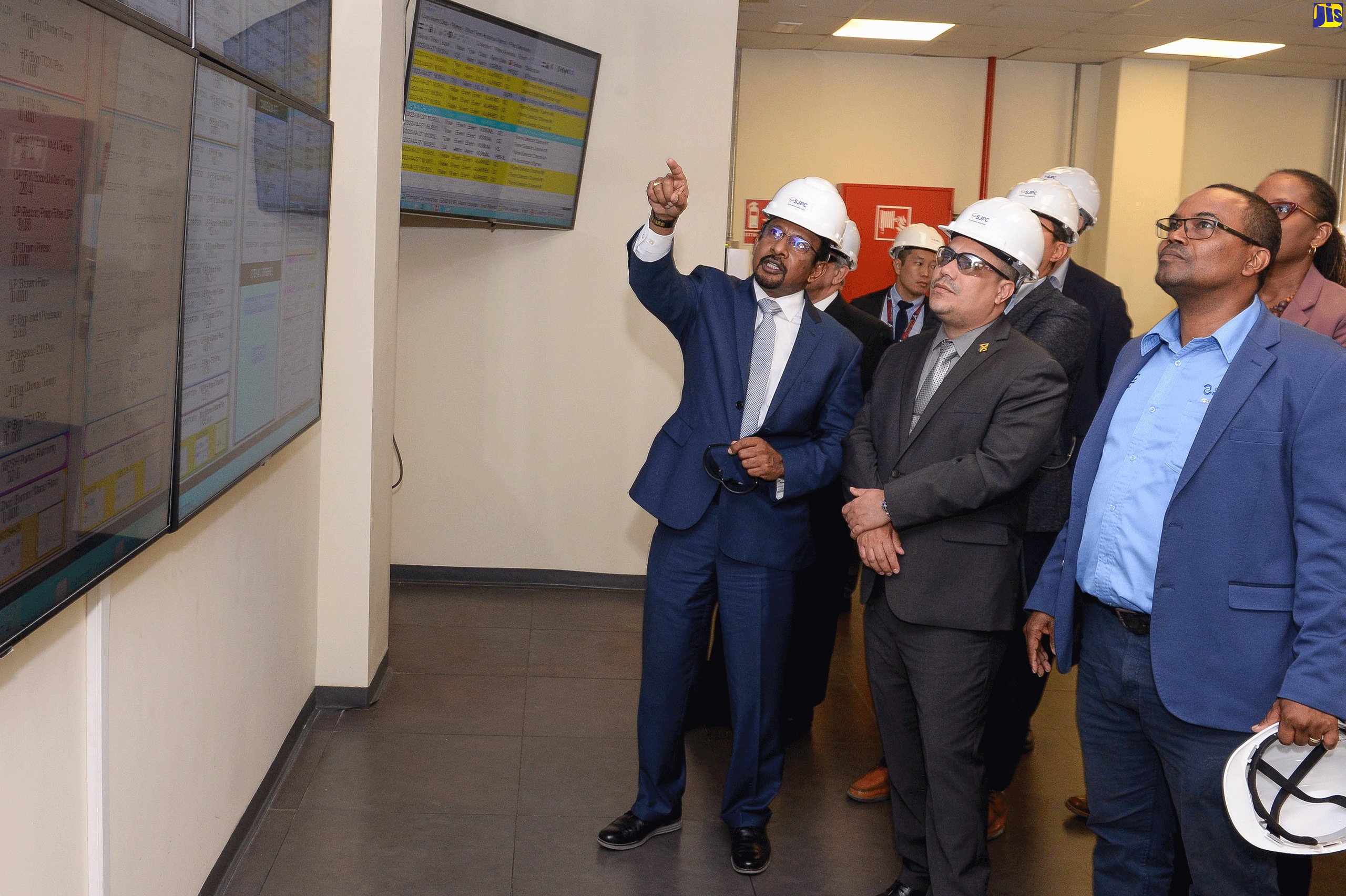Minister without Portfolio in the Ministry of Economic Growth and Job Creation, Senator the Hon. Matthew Samuda (centre) looks at something being pointed out by Chairman, South Jamaica Power Company, Mohamed Majeed (left). Occasion was a tour of the company