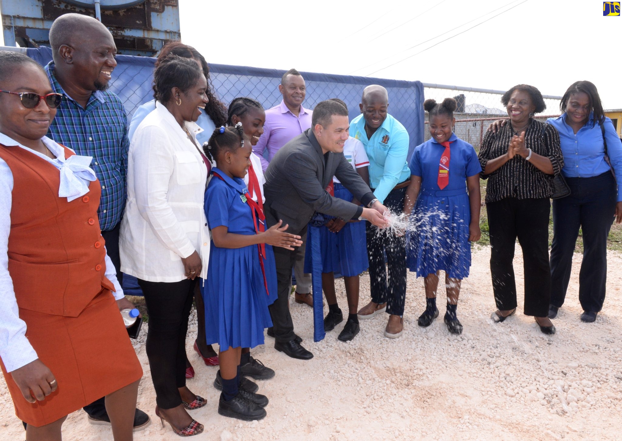 Minister without Portfolio in the Ministry of Economic Growth and Job Creation, Senator the Hon. Matthew Samuda (in jacket), and Member of Parliament for Clarendon South East, Hon. Pearnel Charles Jr. (fourth right), officially commission the Mitchell Town Pipeline Replacement Project, at the Mitchell Town Community Centre on April 20. Sharing the occasion are students from the Mitchell Town Primary School and personnel from the National Housing Trust (NHT) and the National Water Commission (NWC).