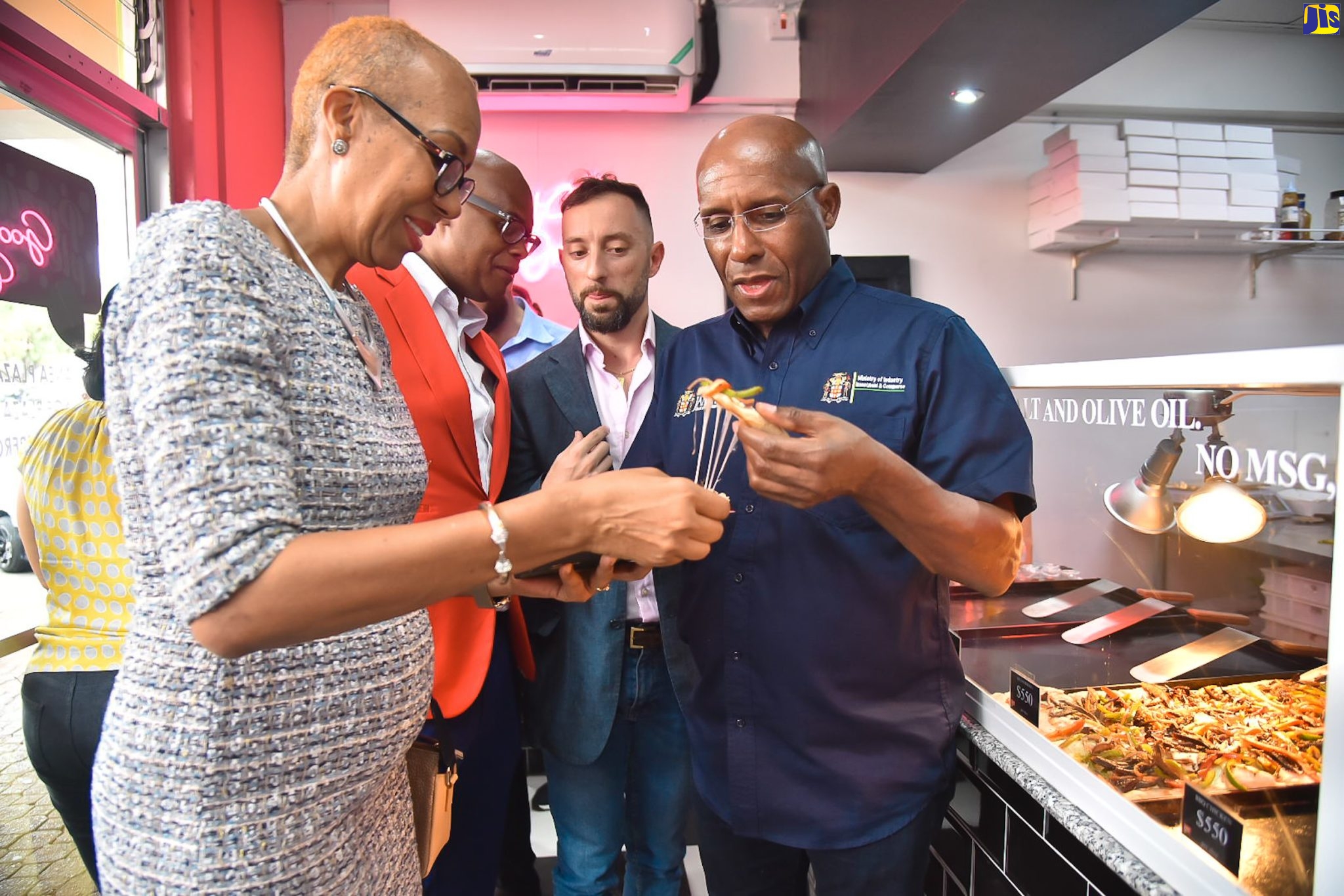 Minister of Industry, Investment and Commerce, Senator the Hon. Aubyn Hill (right), and Minister of Education and Youth, Hon. Fayval Williams (left), sample cuisine prepared at the Liguanea branch of Pizza Please! Restaurant, following the location’s official opening on Saturday (May 13). Looking on are Pizza Please! Director of Operations and Development, Dr. Anthony Claire (second left), and Owner and Director, Pietro Giuliani. The new outlet is located at Shop 16, Liguanea Plaza, Old Hope Road.