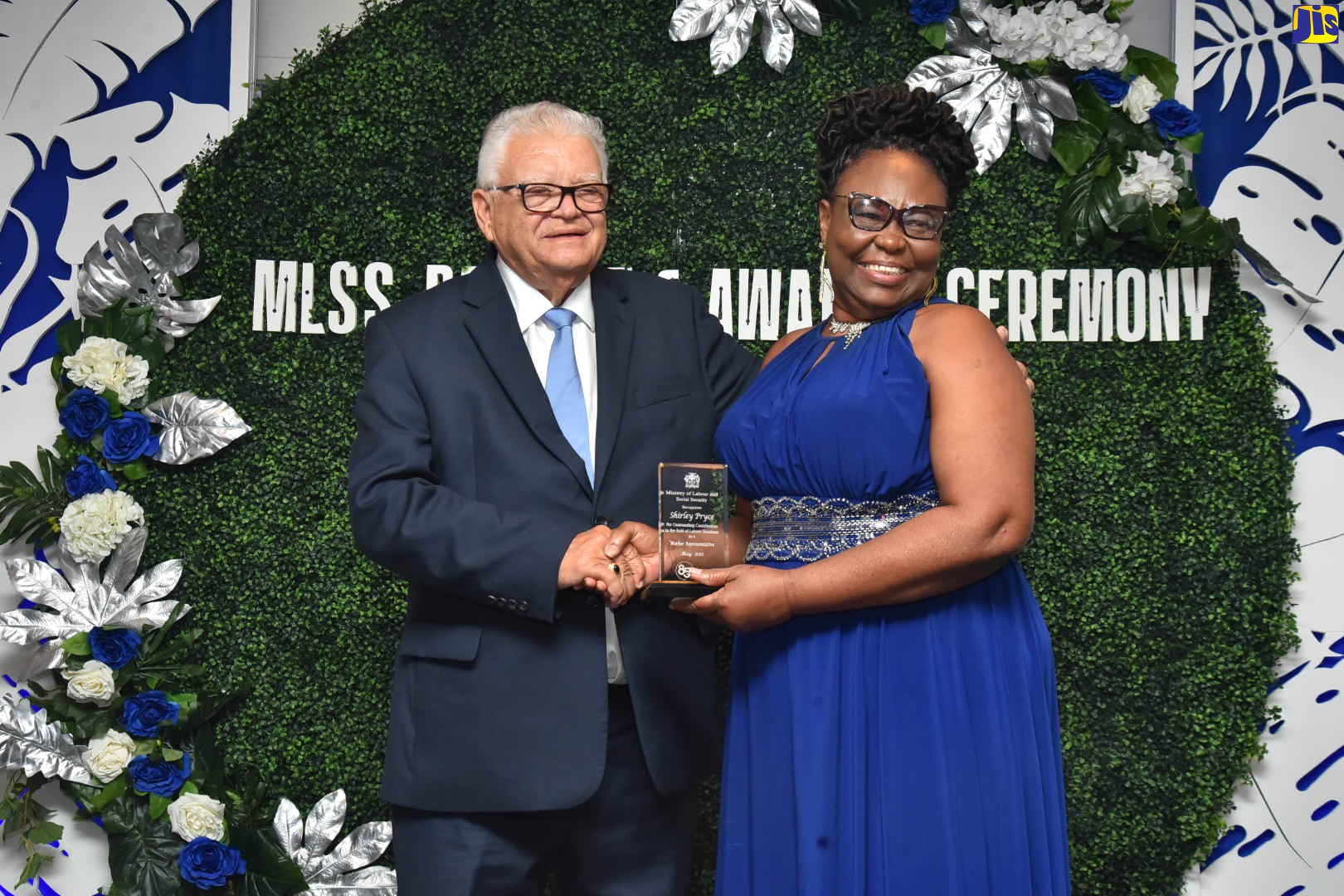 Minister of Labour and Social Security, Hon. Karl Samuda, makes a presentation to veteran advocate for domestic workers’ rights, Shirley Pryce, during the labour relations awards banquet held on Friday, May 18, at the Jamaica Pegasus Hotel in New Kingston.