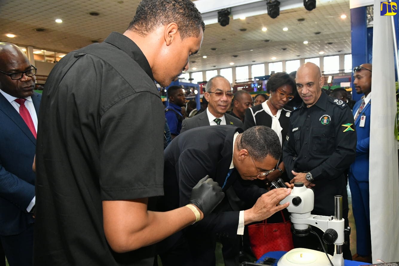 Prime Minister, the Most Hon. Andrew Holness, looks through a microscope while visiting the Institute of Forensic Science and Legal Medicine booth, during the opening ceremony for the Jamaica Constabulary Force’s (JCF) inaugural ‘Transformations 2023: People, Quality and Technology Expo’, on Thursday (May 11) at the National Arena in Kingston. Among those looking on are Deputy Prime Minister and Minister of National Security, Hon. Dr. Horace Chang (fourth right); Police Commissioner, Major General Antony Anderson (second right); Deputy Police Commissioner Fitz Bailey (left); and Forensic Ballistics Expert, Assistant Superintendent of Police, Miguel Bernard (second left).