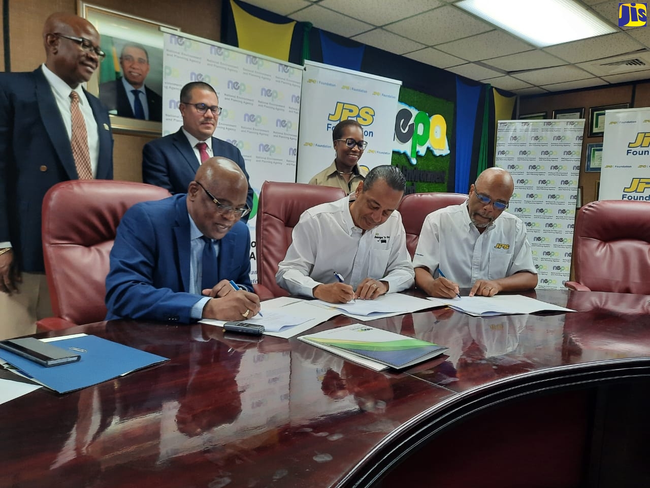 From left (seated): Chief Executive Officer at the National Environment and Planning Agency (NEPA), Peter Knight; Chief Operating Officer at the Jamaica Public Service (JPS) Company Limited, Gary Barrow and Deputy Chairman of the JPS Foundation Limited, Ramsay McDonald, sign a non-binding Memorandum of Understanding for NEPA’s ‘Adopt-A-Mangrove’ programme, at the Agency’s headquarters in Kingston, on Thursday, May 18. Witnessing the signing are (from left, standing) NEPA’s Director of Planning, Projects, Monitoring, Evaluation and Research Division, Ainsworth Carroll; Minister without Portfolio in the Ministry of Economic Growth and Job Creation, Senator the Hon. Matthew Samuda and Director of the JPS Foundation Limited, Winsome Callum. 