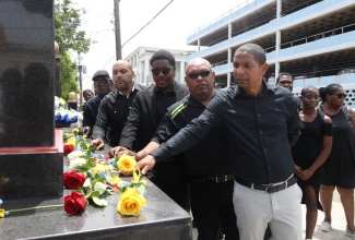 Kingston’s Mayor, Senator Councillor Delroy Williams (right) and Chief Executive Officer, Kingston and St. Andrew Municipal Corporation (KSAMC), Robert Hill (second left), are joined by several stakeholders in laying flowers at the ‘Secret Gardens’ Monument on Friday (June 23) in observance of the National Day of Mourning for Jamaica’s Children who have been victims of violence and abuse. The Monument, which is located at the intersection of Church and Tower Streets in downtown Kingston, was erected by the KSAMC.