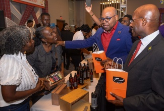 Minister of Tourism, Hon. Edmund Bartlett (second right) and Minister of Industry, Investment and Commerce, Senator the Hon. Aubyn Hill (right), interact with co-owners of Irie Gourmand, Andrea (second left) and Colleen Sybblis, at the opening of the ninth staging of ‘Christmas in July’ at the AC Marriott Hotel in Kingston on Wednesday (July 12).