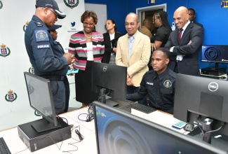 Minister of National Security, Hon Dr. Horace Chang (second right) and Police Commissioner, Major General Antony Anderson (right), observe as Constable Oshane McKenzie (seated) demonstrates the features of the Jamaica Constabulary Force (JCF) upgraded Case Management System. Others (from left) are Senior Superintendent of Police Aaron Fletcher, Sergeant Shermaine Hassack and Permanent Secretary in the Ministry, Ambassador Alison Stone Roofe. Computers valued US$700,000 were handed over to the JCF for the enhancement of the Station Records and Case Management Systems during a ceremony at the National Police College of Jamaica (NPCJ) on Wednesday (July 19).