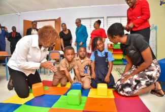 Executive Director of the Early Childhood Commission, Karlene DeGrasse Deslandes (left) and Chief Executive Officer of Digicel Foundation Jodi-Ann McFarlane, play with children on the colour-coded mat inside the new Inclusive Classroom at Bethabara Infant School, which was officially opened on July 5.