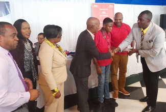 Principal of the St. Catherine-based Old Harbour High School, Lynton Weir (right), makes cash presentation to Principal of the Charlemont High School, Garth Gayle (centre), in support of the school’s band, which performed at the Region 6 back-to-school conference held on Tuesday (July 11), at the Terra Nova All-Suite Hotel in St. Andrew. The funds were donated by participants at the event. Among those sharing the moment are Acting Chief Education Officer, Dr. Kasan (second left), Regional Director in the Ministry, Sophia Forbes Hall (third left).