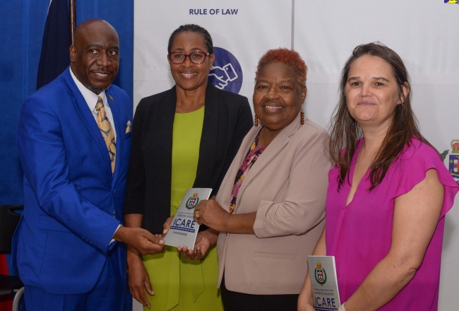 Reverend Courtney Faulknor (left) from the Jamaica Constabulary Force’s (JCF) Chaplaincy, accepts a copy of a Domestic Violence Handbook from Representative of the United Nation’s Population Fund (UNFPA) for the English and Dutch-speaking Caribbean, Elizabeth Talbert (second right). The handover took place during the graduation ceremony for the Domestic Violence Intervention Centre’s (DVIC) Domestic Violence Train-the-Trainer Course, at the National Police College of Jamaica (NPCJ) in St. Catherine on Friday (July 21). Sharing the moment are Head of the JCF’s Community Safety and Security Branch, Assistant Commissioner of Police (ACP), Charmine Shand (second left), and Gender-Based Specialist, UNFPA, Elga Salvador.