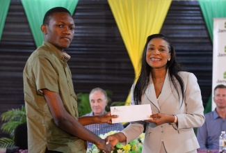 Managing Director, HEART/NSTA Trust, Dr. Tanesha Ingleton (right), presents Jamalco Education Assistance Programme scholarship recipient, Antonio Pink, with a commitment letter during the presentation ceremony on Wednesday (August 16) at the Wembley Centre of Excellence in Clarendon.