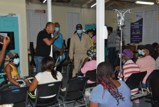 Minister of Health and Wellness, Dr. the Hon. Christopher Tufton, addresses patients seated in the accident and emergency waiting area at the Cornwall Regional Hospital in Mt. Salem, St. James, on Friday, August 11.