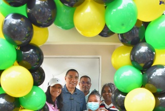 Prime Minister, the Most Hon. Andrew Holness (second left), makes a presentation to Blenheim, Manchester resident, Carla Pinnock, who is the recipient of a two-bedroom home, built in the community under the New Social Housing Programme (NSHP). Prime Minister Holness presented Ms. Pinnock with the keys on Friday (July 14). Sharing the occasion are (from left) Members of Parliament for Manchester Central, Rhoda Moy Crawford, and Manchester Southern, Robert Chin; and Principal Finance Officer, Ministry of Economic Growth and Job Creation, Judith Robb-Walters, who chairs the NSHP Oversight Committee