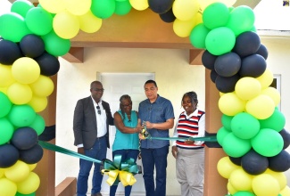Prime Minister, the Most Hon. Andrew Holness (second right), cuts the ribbon prior to handing over a three-bedroom house built under the New Social Housing Programme (NSHP) to beneficiary, Marjorie Darien (second left), in Thornton, St. Elizabeth, on Friday (July 14). Sharing the moment (from left) are Member of Parliament, St. Elizabeth North Eastern, Delroy Slowley, and Principal Financial Officer, Ministry of Economic Growth and Job Creation, Judith Robb-Walters.