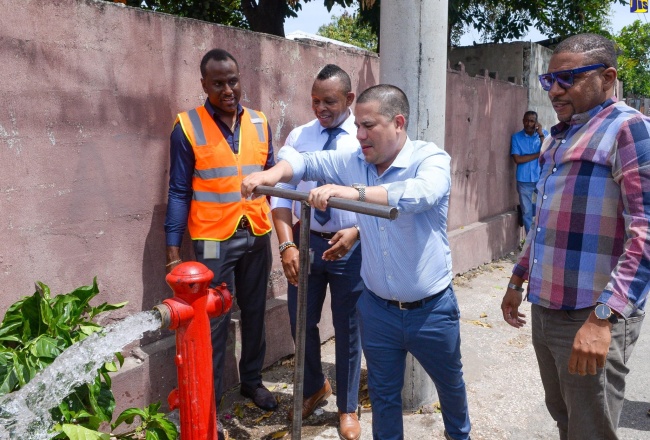 Minister without Portfolio in the Ministry of Economic Growth and Job Creation, with responsibility for Water, Environment and Climate Change, Senator the Hon. Matthew Samuda (second right), symbolically turns on water at a fire hydrant during a tour of the Waltham Park Road pipeline replacement project area in Kingston, on June 22. Looking on are (from left) Non-Revenue Water (NRW) and Water Supply Manager, National Water Commission (NWC), Chadron Stern; Vice President of Operations, NWC, Kevin Kerr and Councillor for the Whitfield Town Division, St. Andrew South Western, Eugene Kelly.
