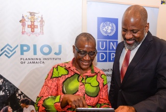 Director General, Planning Institute of Jamaica (PIOJ), Dr. Wayne Henry (right), and United Nations Development Programme (UNDP) Resident Representative, Denise Antonio, view the website for the PIOJ’s ‘Data 4 Development’ Online Monitoring Platform, during the official launch of the Platform at the Marriott Courtyard Hotel in Kingston on Thursday (June 22).