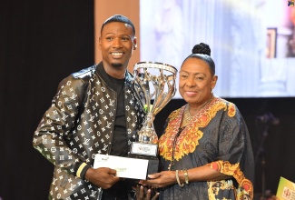 Minister of Culture, Gender, Entertainment and Sport, Hon. Olivia Grange, presents the 2023 Jamaica Gospel Star winner, Oral Lawson, with the trophy at the grand finals of the Jamaica Cultural Development Commission (JCDC)-organised competition, which was held on August 2 at the National Arena.