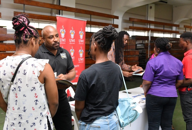 Director of Children and Family Programmes at the Child Protection and Family Services Agency (CPFSA), Dr. Warren Thompson (centre), speaks with two youths in State care, during the agency’s Transitional Living Expo, held at the National Arena in Kingston, recently.