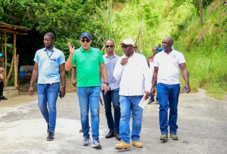 Minister without Portfolio in the Ministry of Economic Growth and Job Creation, Hon. Everald Warmington (second right), and Member of Parliament for St. Catherine West Central, Dr. the Hon. Christopher Tufton (second left), on a tour of roads earmarked for repairs in the area, on July 19. Also pictured are personnel from the National Works Agency (NWA) and community members.