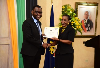 Sergeant Kensley Shay of the Jamaica Constabulary Force collects his award as one of the recipients of the Marcus Garvey Public Graduate Scholarship from Minister of State in the Ministry of Finance and the Public Service, Hon. Marsha Smith, at a ceremony held at King’s House, on August 17, 2022.