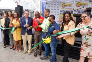 Minister of Science, Energy, Telecommunication and Transport, Hon. Daryl Vaz (fourth left), participates in the cutting of ribbon to officially open the Grennell’s Driving School Crash Free Defensive Driving Workshop and Expo held on Wednesday (June 28), at S Foods Supermarket Parking Lot in New Kingston. He is joined by Director of Grennell’s Driving School, Alphanso Grennell (fifth left) and representatives of corporate sponsors of the event.