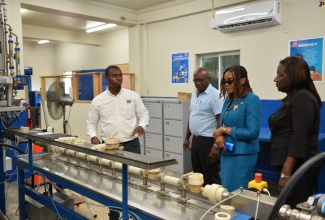 National Water Commission (NWC) Meter Testing Lab Supervisor, Shevaughn Williams (left), leads a tour of the Instrumentation and Meters Laboratory, which was officially opened at the entity’s head office on Marescaux Road in Kingston on Wednesday (July 19). Others pictured (from right) are Coordinator of the National Accreditation Focal Point, Sonia Morgan; Chief Executive Officer (CEO) of the Jamaica National Agency for Accreditation (JANAAC), Sharonmae Shirley and NWC Assistant Vice President of Maintenance, Aubrey Williams.