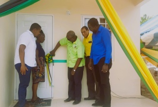 Minister of Local Government and Community Development, Hon. Desmond McKenzie (centre), cuts ribbon to officially hand over a new Indigent Housing Programme unit to beneficiary Bernicey Wright (second left) in Black River, St. Elizabeth, on June 22. Also taking part are (from left) Minister of Agriculture, Fisheries and Mining and Member of Parliament for St. Elizabeth Southwestern, Hon. Floyd Green; Mayor of Black River, Councillor Derrick Sangster and Councillor for the Black River Division, Dwight Salmon.