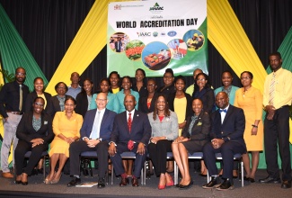 Minister of Industry, Investment and Commerce, Senator the Hon. Aubyn Hill (centre, seated), with executives of the Jamaica National Agency for Accreditation (JANAAC) during the entity’s CEO Breakfast at The Jamaica Pegasus hotel in New Kingston on June 9, where three public and private-sector entities received accreditation to ISO/IEC 17025 Standard. From left (seated) are JANAAC’s Director of Planning, Strategic Development and Promotions, Cassetta Green; Director of Accreditation, Gabrielle Andrade-Bell; Chairman, Simon Roberts; Chief Executive Officer, Sharonmae Shirley; Senior Director of Accreditation, Training and Quality Management, Dr. Yvette Castell; and Director of Finance and Administration, Garfield Bassett. Standing are representatives of the entities – the Jamaica Public Service Company Limited (JPS), National Water Commission (NWC), and National Compliance and Regulatory Authority (NCRA).